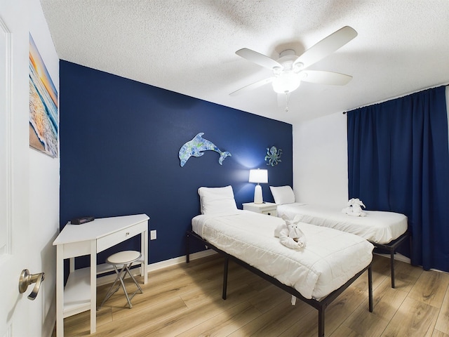 bedroom with ceiling fan, a textured ceiling, and light wood-type flooring