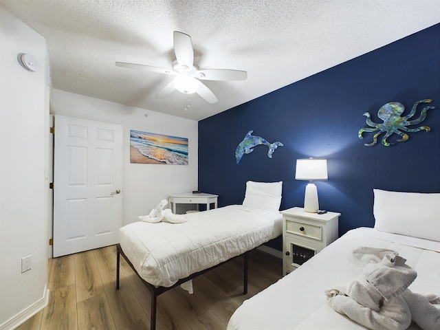 bedroom with a textured ceiling, hardwood / wood-style flooring, and ceiling fan