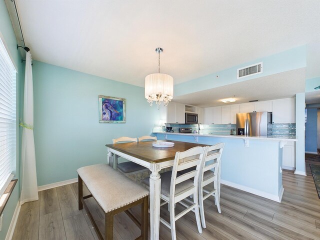 dining room with light hardwood / wood-style floors, sink, and a chandelier