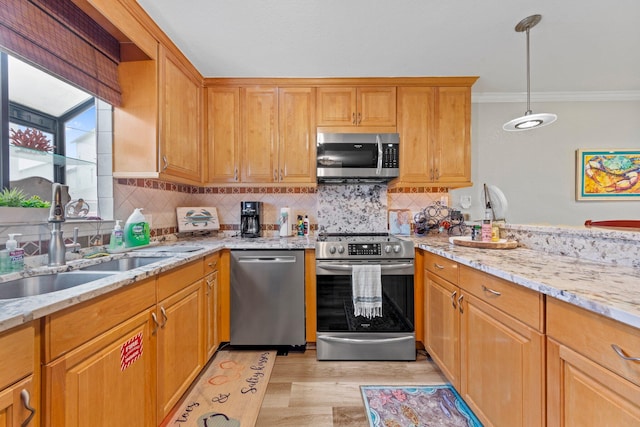 kitchen featuring appliances with stainless steel finishes, backsplash, light wood-type flooring, pendant lighting, and light stone countertops