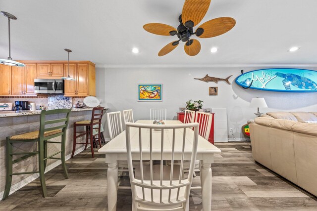 dining area with ceiling fan, crown molding, and hardwood / wood-style flooring