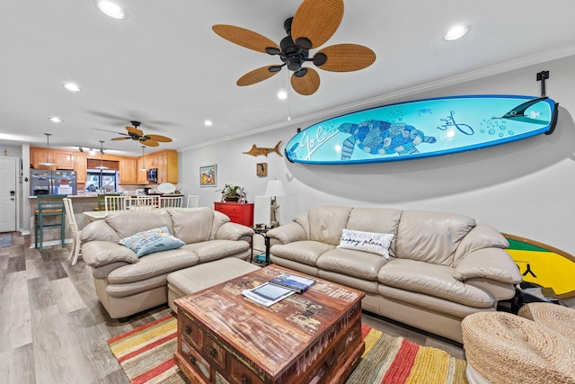 living room featuring ceiling fan, light hardwood / wood-style floors, and ornamental molding