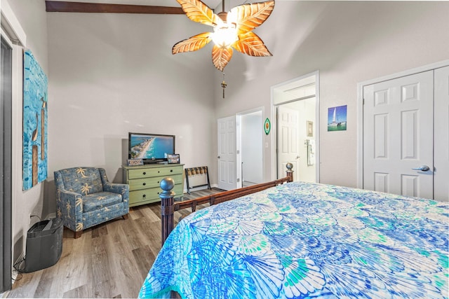 bedroom with wood-type flooring, ceiling fan, and a high ceiling