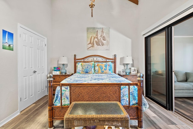 bedroom featuring a closet, light hardwood / wood-style flooring, and a high ceiling