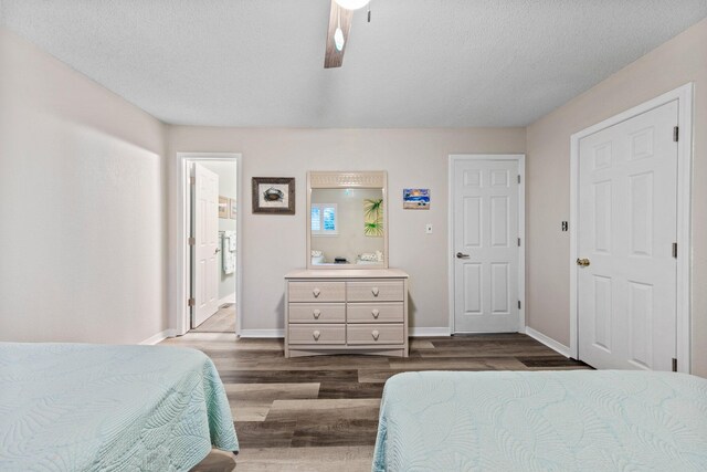 bedroom with ceiling fan, dark hardwood / wood-style flooring, connected bathroom, and a textured ceiling