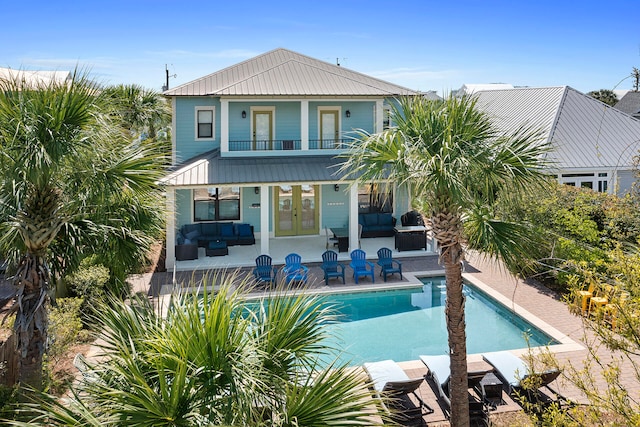 rear view of property featuring a patio area, an outdoor living space, and a balcony