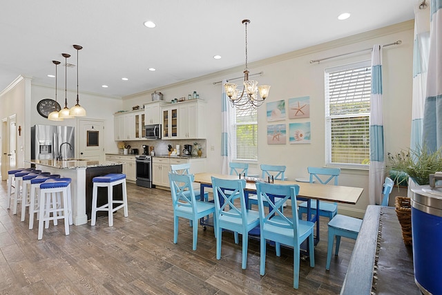 dining area with dark hardwood / wood-style flooring, a chandelier, sink, and crown molding