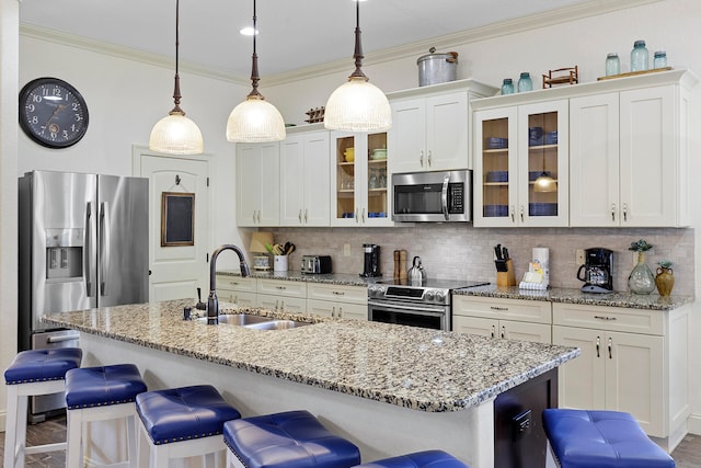 kitchen with appliances with stainless steel finishes, a kitchen bar, sink, tasteful backsplash, and hanging light fixtures