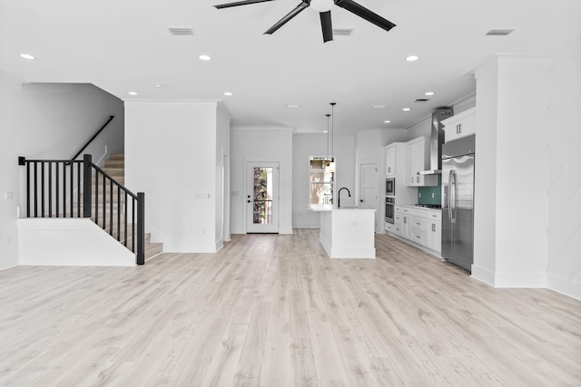 unfurnished living room with sink, ceiling fan, crown molding, and light wood-type flooring