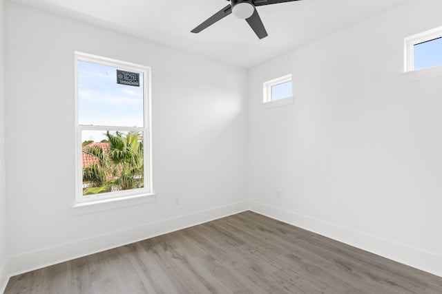 spare room with plenty of natural light, ceiling fan, and dark wood-type flooring