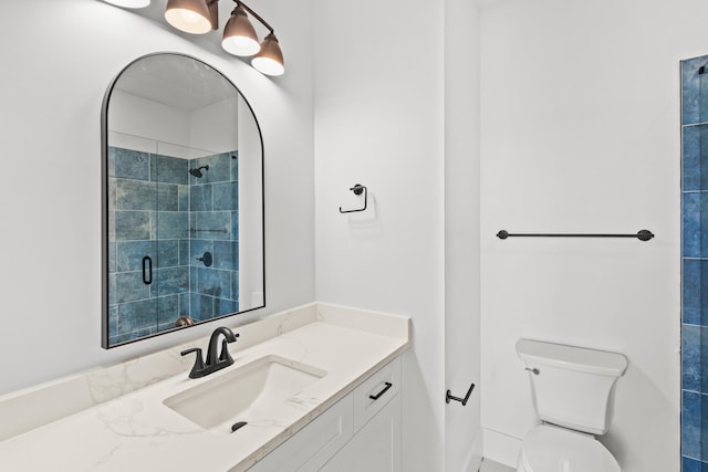 bathroom featuring vanity, toilet, and a tile shower