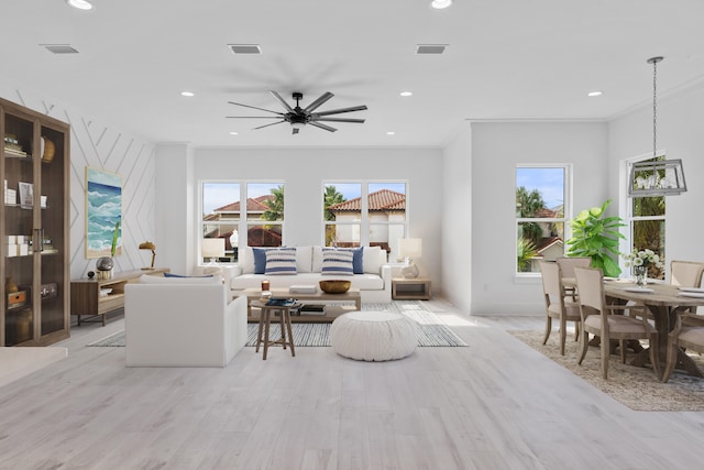 living room with a healthy amount of sunlight, light hardwood / wood-style flooring, ceiling fan, and ornamental molding