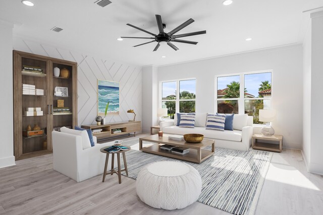 living room with ornamental molding, ceiling fan, and light wood-type flooring