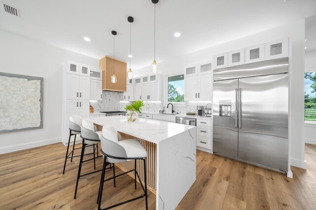 kitchen featuring white cabinets, backsplash, a kitchen island, stainless steel appliances, and sink