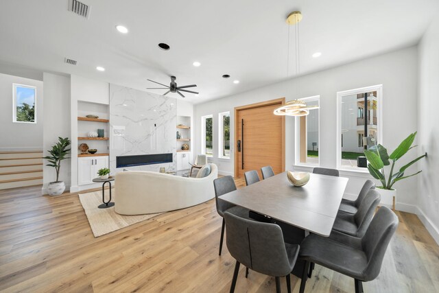 dining room with a fireplace, ceiling fan, built in features, and plenty of natural light