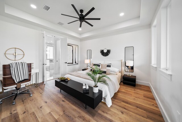 bedroom featuring wood-type flooring, a tray ceiling, and ceiling fan