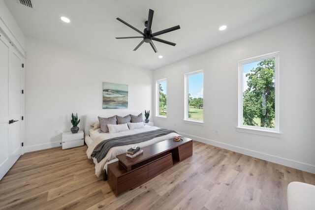 bedroom featuring light hardwood / wood-style floors, ceiling fan, and multiple windows