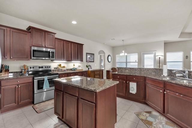 kitchen with appliances with stainless steel finishes, sink, dark stone counters, a chandelier, and pendant lighting