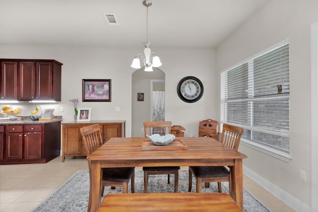 tiled dining room with an inviting chandelier