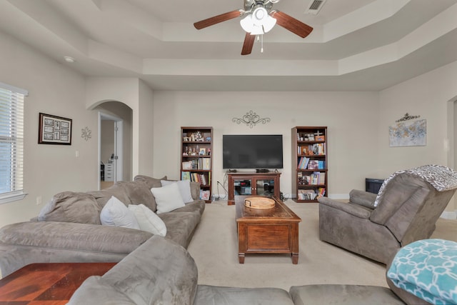 living room featuring light carpet, ceiling fan, and a tray ceiling