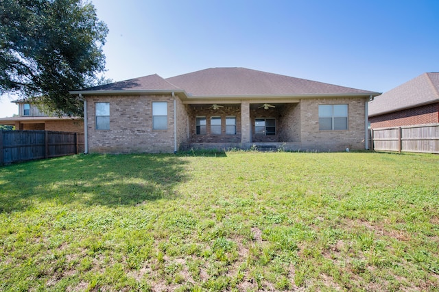 rear view of house with ceiling fan and a yard