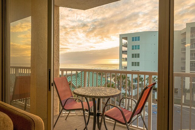 balcony at dusk featuring a water view