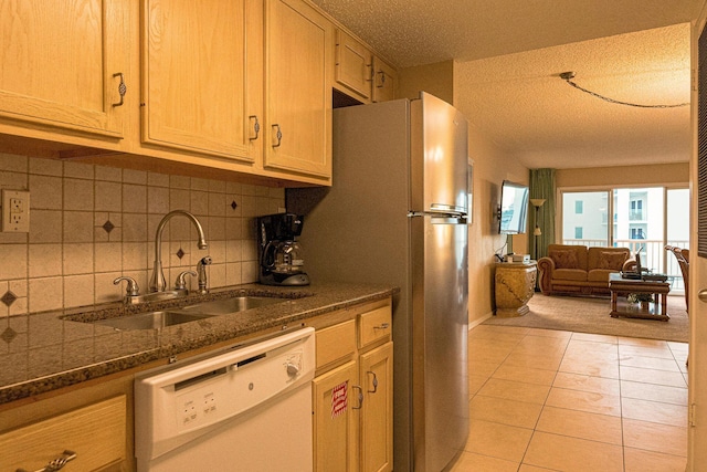 kitchen featuring white appliances, a textured ceiling, tasteful backsplash, dark stone counters, and sink