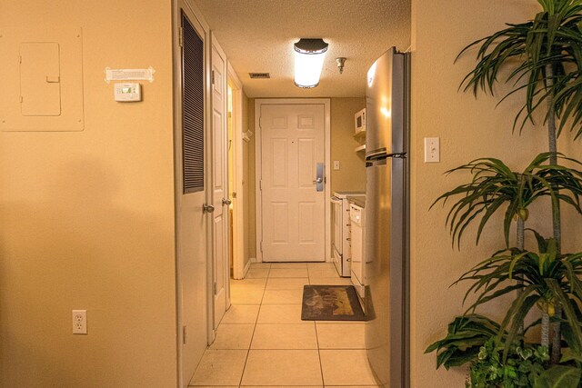 corridor featuring light tile floors and a textured ceiling