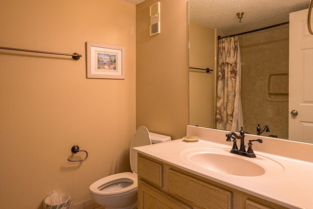 bathroom with a textured ceiling, large vanity, and toilet