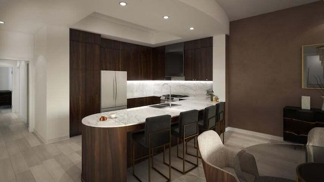 kitchen with white refrigerator, dark brown cabinets, kitchen peninsula, and light wood-type flooring