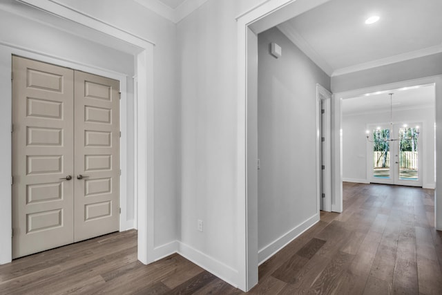 hallway featuring wood-type flooring, ornamental molding, an inviting chandelier, and french doors