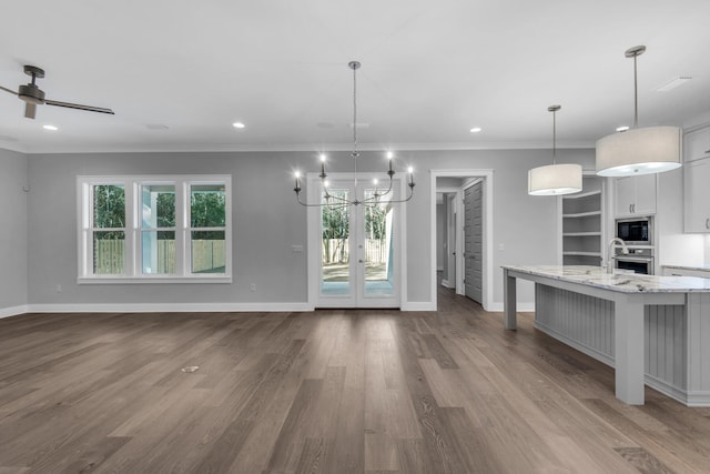 kitchen featuring pendant lighting, a breakfast bar, white cabinets, built in microwave, and light stone countertops