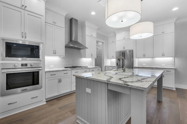 kitchen with white cabinets, appliances with stainless steel finishes, and wall chimney range hood