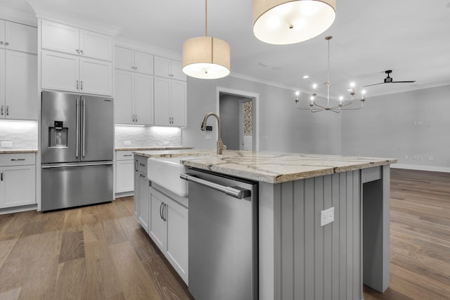 kitchen featuring white cabinets, a kitchen island with sink, appliances with stainless steel finishes, and decorative backsplash