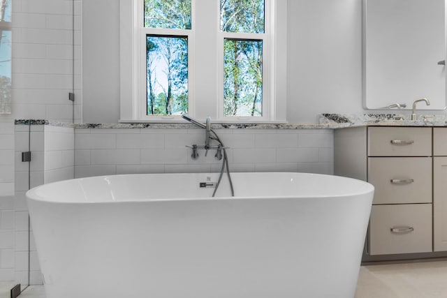 bathroom featuring a bathtub, tile walls, and vanity