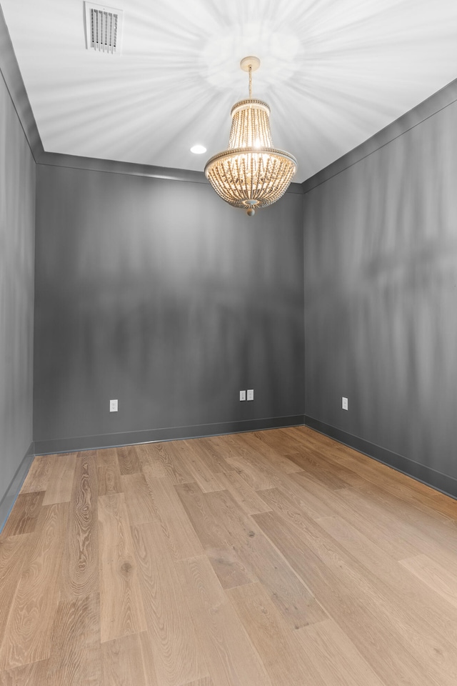 unfurnished room featuring light wood-type flooring and a chandelier