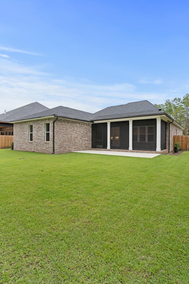 back of property with a sunroom, a patio area, and a yard