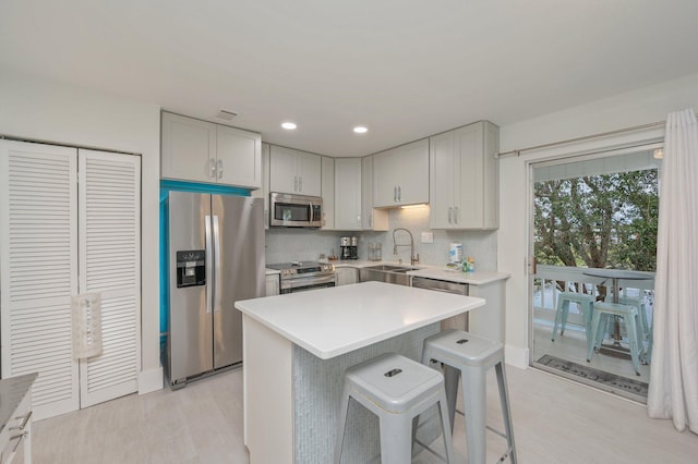 kitchen featuring a center island, backsplash, appliances with stainless steel finishes, a kitchen bar, and sink