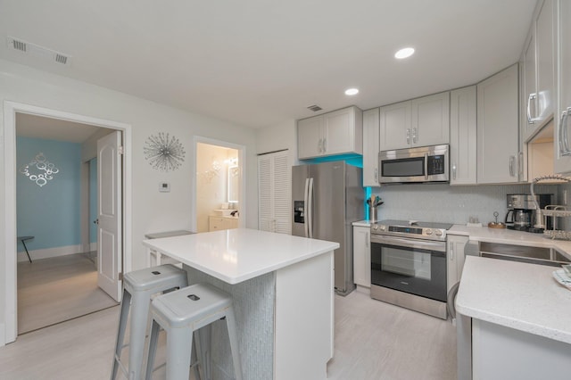 kitchen featuring light hardwood / wood-style flooring, stainless steel appliances, sink, a breakfast bar area, and a kitchen island