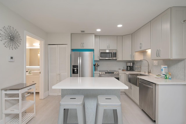 kitchen featuring a kitchen island, sink, stainless steel appliances, light hardwood / wood-style flooring, and a kitchen breakfast bar