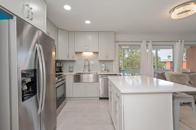 kitchen with sink, appliances with stainless steel finishes, white cabinetry, and a kitchen breakfast bar