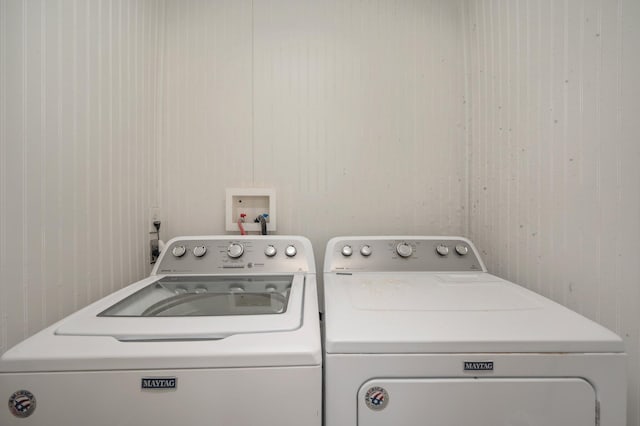 laundry area with washer and clothes dryer, wood walls, and hookup for a washing machine