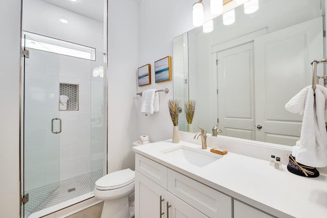 bathroom featuring large vanity, a shower with shower door, and toilet