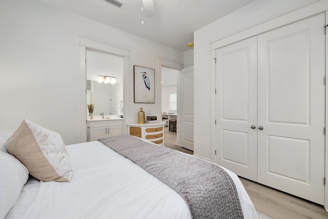 bedroom featuring a closet, ceiling fan, light wood-type flooring, and ensuite bath