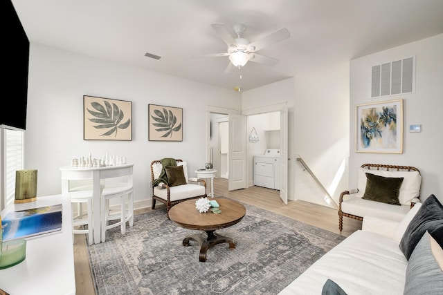 living room featuring ceiling fan, light hardwood / wood-style floors, and washer / clothes dryer