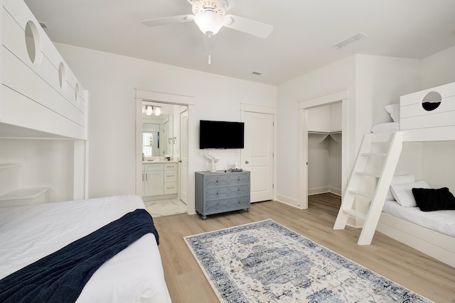 bedroom featuring connected bathroom, a closet, light hardwood / wood-style flooring, and ceiling fan