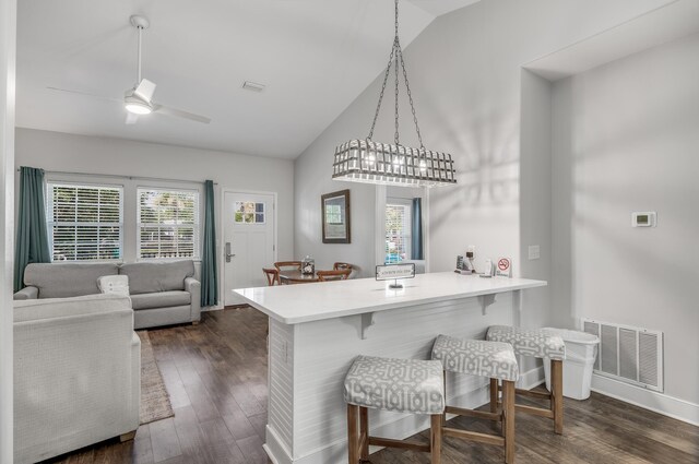 kitchen featuring ceiling fan, dark wood-type flooring, decorative light fixtures, and a kitchen bar