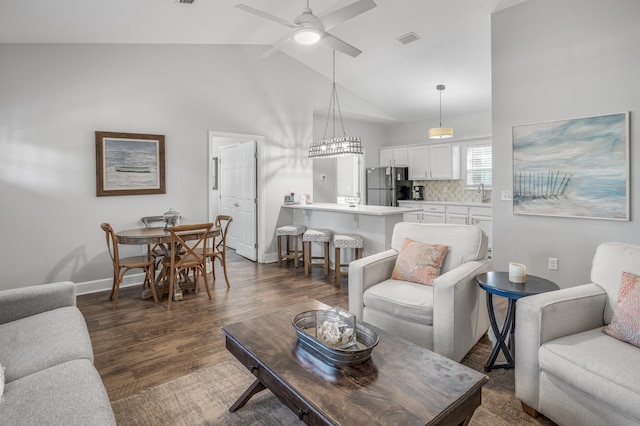 living room with ceiling fan with notable chandelier, high vaulted ceiling, dark hardwood / wood-style flooring, and sink