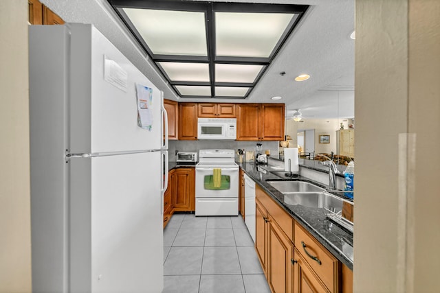 kitchen with ceiling fan, light tile floors, sink, white appliances, and dark stone countertops