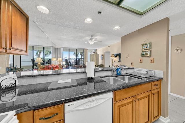 kitchen featuring ceiling fan, white dishwasher, dark stone countertops, sink, and light tile floors